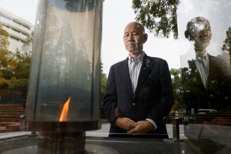 　「１・１７希望の灯り」を見つめる百々孝治さん。阪神大震災で妻子を亡くした＝２０２５年１１月、神戸市中央区の東遊園地