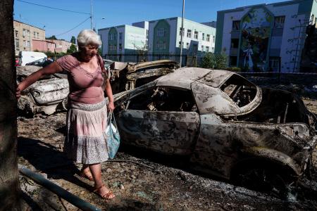 　ロシアの攻撃で損壊した車の横を歩く地元女性＝４日、ウクライナ・キーウ（ＡＰ＝共同）