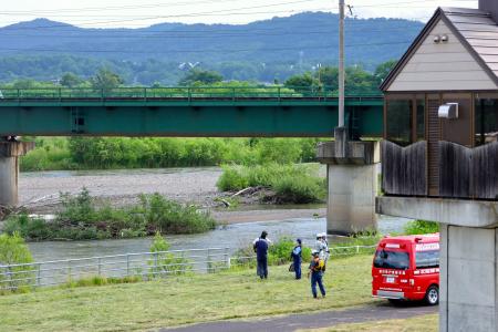 　石狩川の河川敷を調べる警察官ら＝２３日午後４時３０分ごろ、北海道旭川市川端町