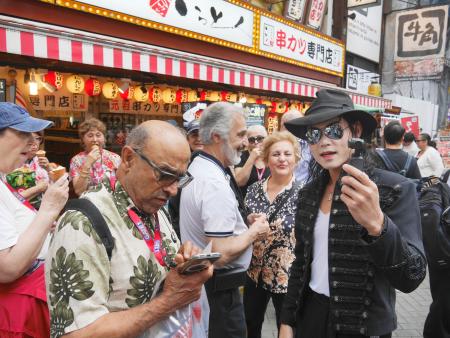　訪日客と交流しながらマナーアップを啓発するマイケル・ジャクトンさん（右端）＝５月、大阪・道頓堀