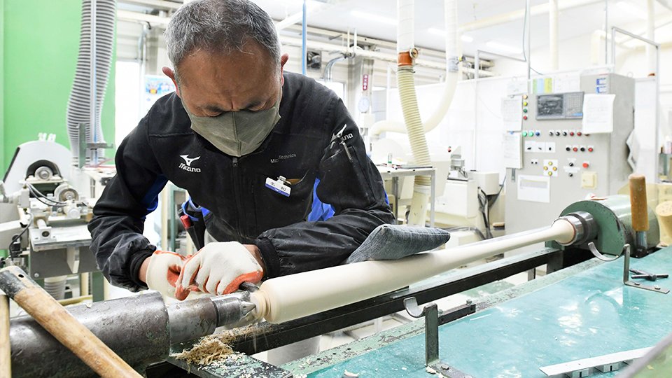 高速回転させた木材にのみを押し当ててバットを削るクラフトマン