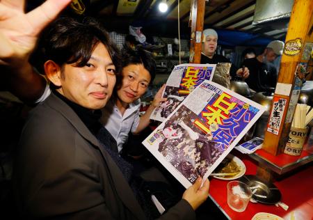 　ソフトバンクの日本一を伝える号外を手に、福岡・天神の屋台で喜ぶ客＝３０日夜