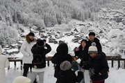 雪と記念撮影する観光客ら＝２１日午後０時２８分、大野郡白川村荻町、荻町城跡展望台