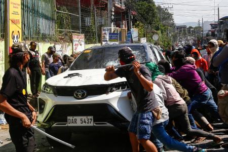 　フィリピン・ミンダナオ島コタバトで、投票所の外で対立するグループの車を襲撃する一団＝１４日（ＡＰ＝共同）