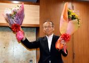 　千葉県船橋市長選で４選が確実となり、花束を手に笑顔の松戸徹氏＝２２日夜、千葉県船橋市
