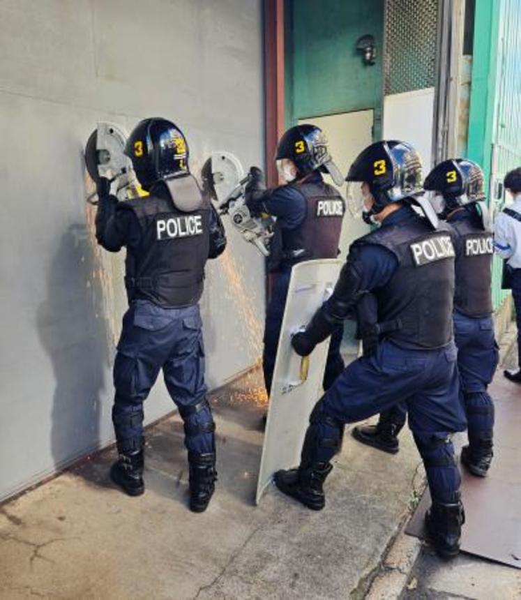 　家宅捜索のため、中核派拠点「前進社」の扉をエンジンカッターで切る警視庁の機動隊員＝３０日午前８時２６分、東京都江戸川区