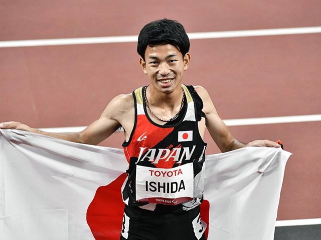男子１００ｍ（Ｔ４７）決勝で５位入賞を果たし、日の丸を背に喜ぶ石田駆＝国立競技場