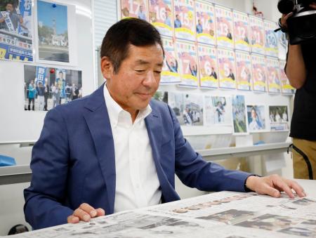 　再選から一夜明け、選挙結果が掲載された新聞を読む立憲民主党の勝部賢志氏＝２１日午前、札幌市