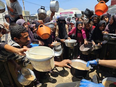 　１５日、ガザ南部ハンユニス西方マワシ地区で、援助団体が配る温かい食べ物を受け取ろうとするパレスチナ人（ゲッティ＝共同）