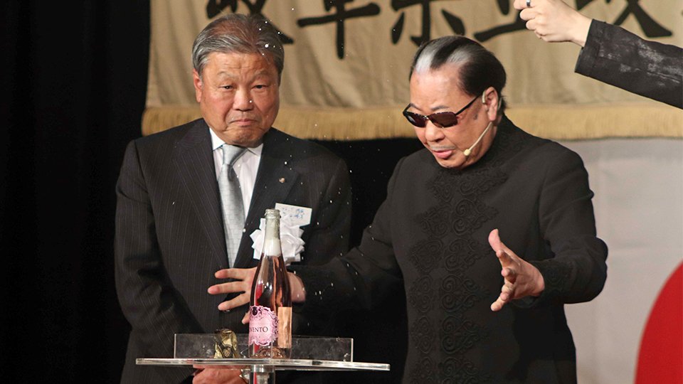 岩田勝美同窓会長（左）の前で、ハンドパワーによるシャンパン栓抜きを披露するＭｒ．マリックさん＝岐阜市柳ケ瀬通、ホテルグランヴェール岐山