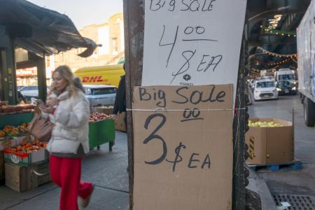 　米ニューヨークの商店街で価格表示の傍らを歩く通行人＝２０２５年１２月１２日（ゲッティ＝共同）