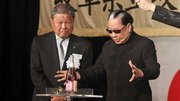 岩田勝美同窓会長（左）の前で、ハンドパワーによるシャンパン栓抜きを披露するＭｒ．マリックさん＝岐阜市柳ケ瀬通、ホテルグランヴェール岐山
