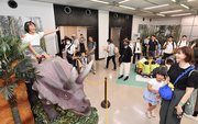 トリケラトプスのロボットの背に乗り、笑顔を見せる女の子＝岐阜市本荘、市科学館（撮影・山田雄大）