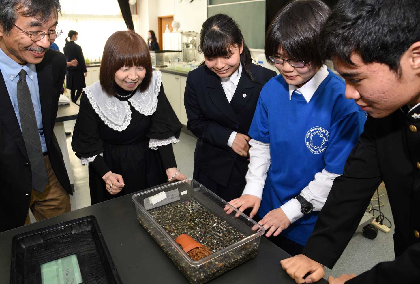 ヤマトサンショウウオを飼育しているケースを前に歓談する部員とイルカさん（左から２番目）ら＝岐阜市大縄場、岐阜高校