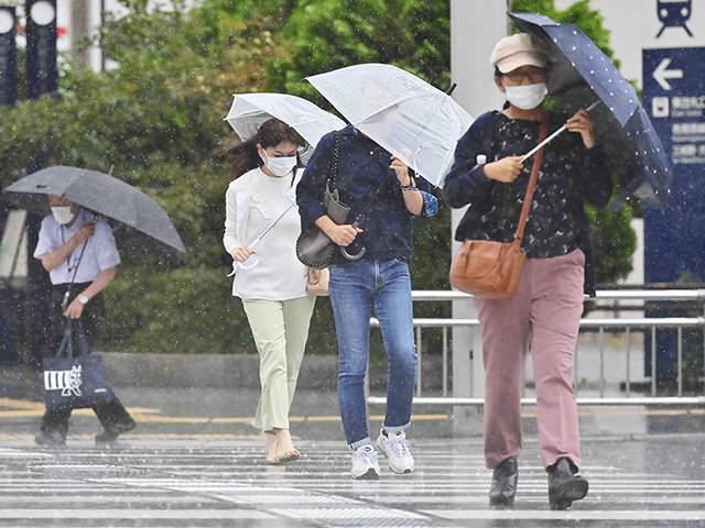 強い風雨の中、傘を傾けて横断歩道を渡る人たち＝１３日午後４時、岐阜市神田町、名鉄岐阜駅前