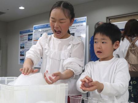 　南極について学ぶイベントで、氷に触れる子どもたち＝２１日午後、広島市中区