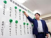 　東京都議選の開票が進む中、当確者の名前にバラを付ける都民ファーストの会の森村代表＝２２日深夜、青梅市