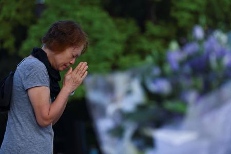 　平和記念公園の原爆慰霊碑の前で祈りをささげる女性＝６日、広島市（ロイター＝共同）