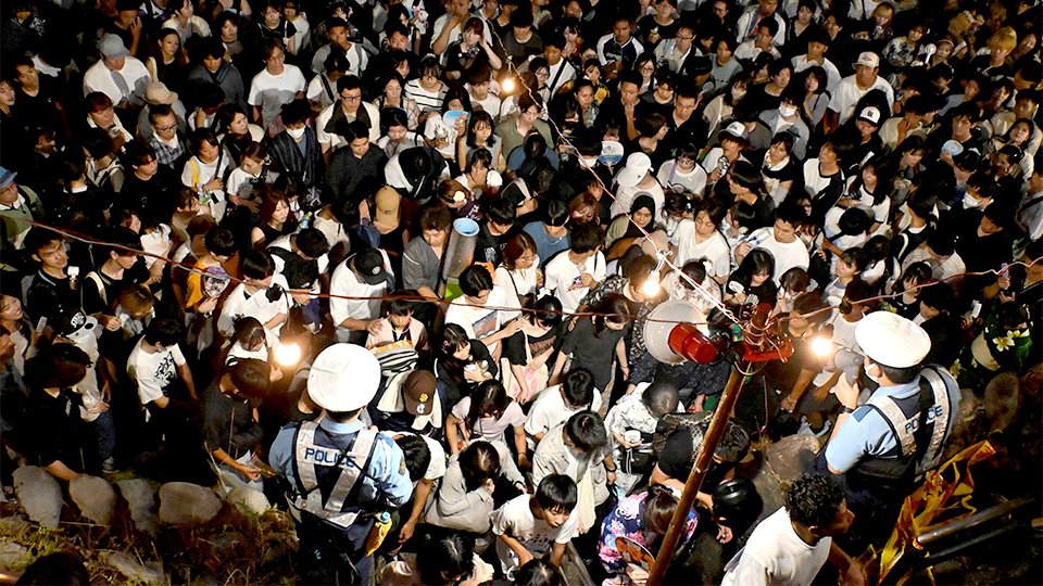 押し寄せる観衆に「前の人を押さないで」と呼びかけて誘導する警察官たち＝岐阜市、長良川河畔