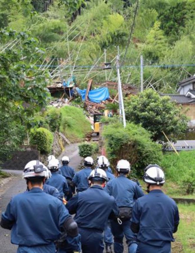 　大雨で土砂が流入し倒壊した住宅（奥）に向かう警察官ら＝１０日午前、鹿児島県姶良市