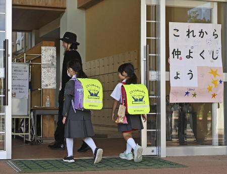 　「これから仲よくしよう」のボードが掲げられた石川県能登町立柳田小に入る輪島市立町野小の児童ら＝昨年１０月、能登町