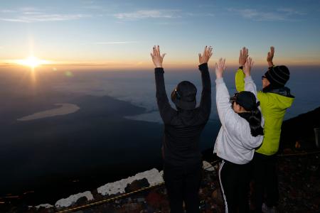 　山開きを迎えた富士山の山頂で、御来光に向かって万歳する登山客ら＝１日午前４時３８分