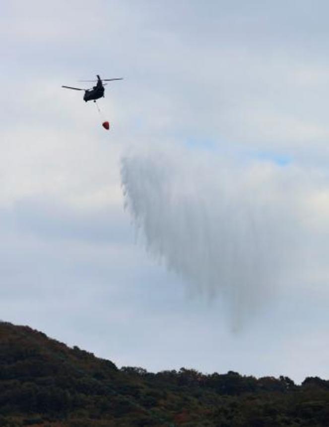 　大分市佐賀関の大規模火災現場付近で上空から散水する自衛隊のヘリコプター＝２０日午前１０時２６分