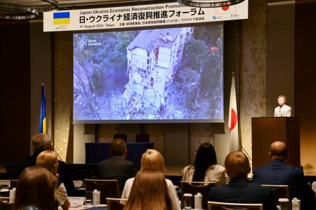 　日・ウクライナ経済復興推進フォーラムで講演するウクライナのゼレンスキー大統領の妻オレナさん（右奥）＝４日午前、東京都内