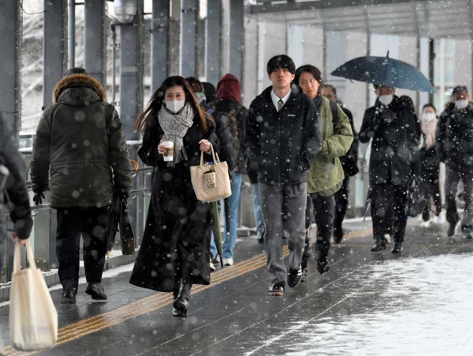 雪が降る中を出勤する人たち＝５日午前７時３８分、岐阜市神田町