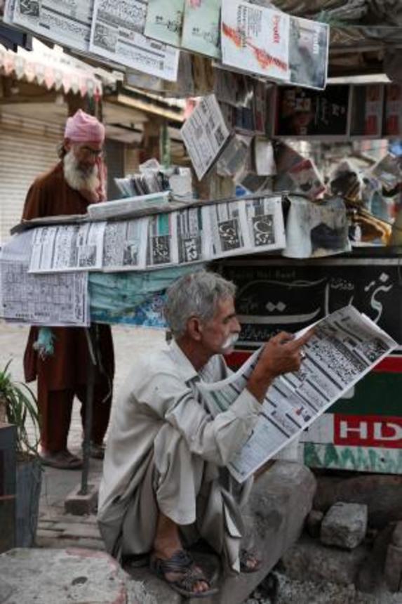 　パキスタンの首都イスラマバードで、米イランの戦闘終結に向けた覚書を巡るニュースを読む男性＝１４日（ロイター＝共同）