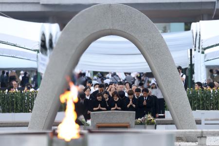 　米軍の原爆投下から８０年の「原爆の日」となり、慰霊碑に手を合わせる人たち＝６日午前５時３６分、広島市中区の平和記念公園