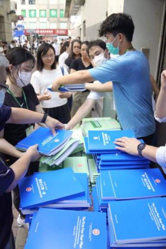　香港の街頭で配布される「５カ年計画」の冊子＝１６日（共同）