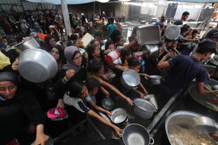　ガザ中部ヌセイラト難民キャンプで、配給の食べ物を受け取ろうとする人たち＝１６日（ゲッティ＝共同）