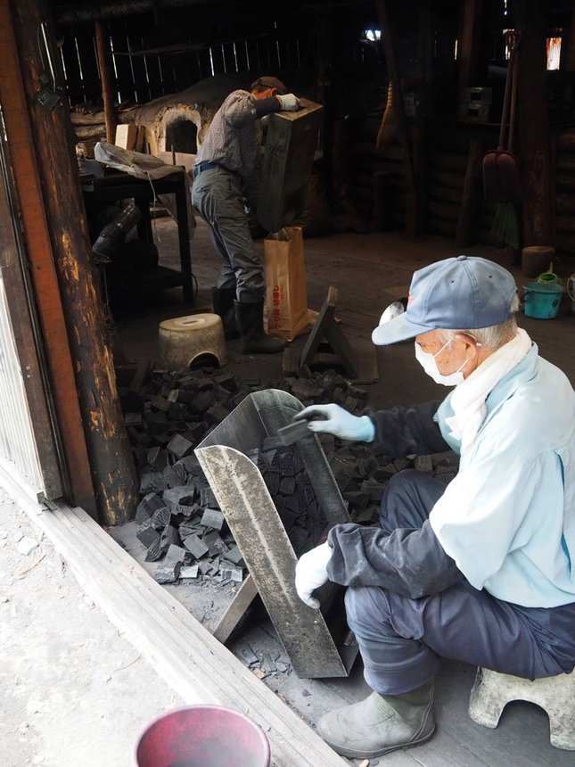 ナラ炭を袋に詰める葛巻町森林組合の職人たち＝岩手県葛巻町