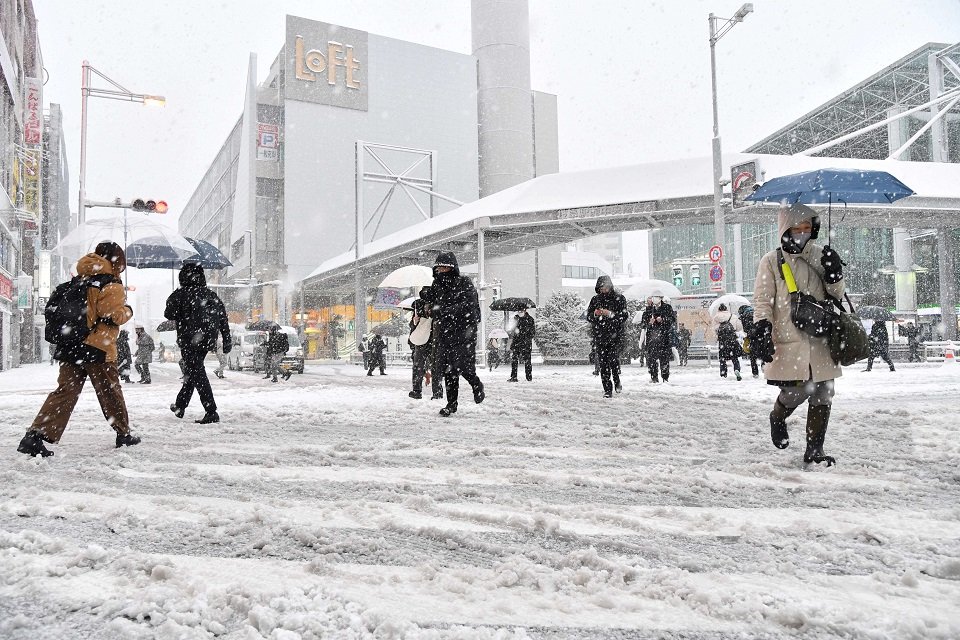 雪が積もった道路を慎重に歩く人たち＝２４日午前７時３０分、岐阜市の名鉄岐阜駅前