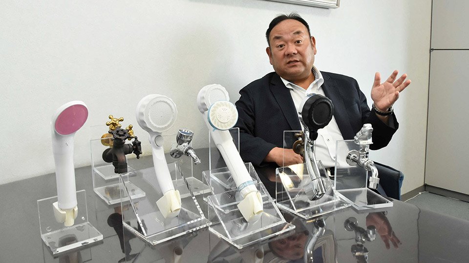 製造する蛇口やシャワーヘッドを紹介しながら、山県市の水栓バルブの歴史を説明する早川徹社長＝同市東深瀬、水生活製作所