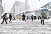 雪が積もった道路を慎重に歩く人たち＝２４日午前７時３０分、岐阜市の名鉄岐阜駅前