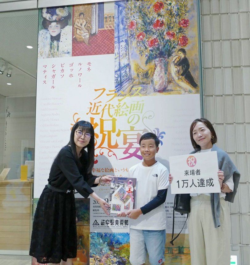 １万人目の来場者として記念品を受け取る（右から）小山由里子さん、宗士朗さん親子＝岐阜市宇佐、県美術館