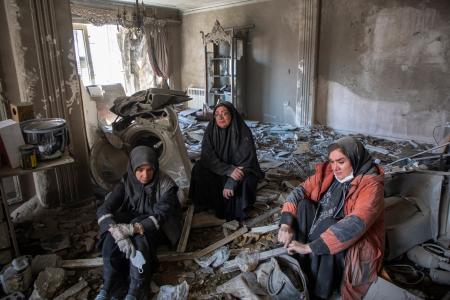 　イランの首都テヘランで、攻撃で壊れた住宅のがれきの上に座り込む住民たち＝３０日（ゲッティ＝共同）