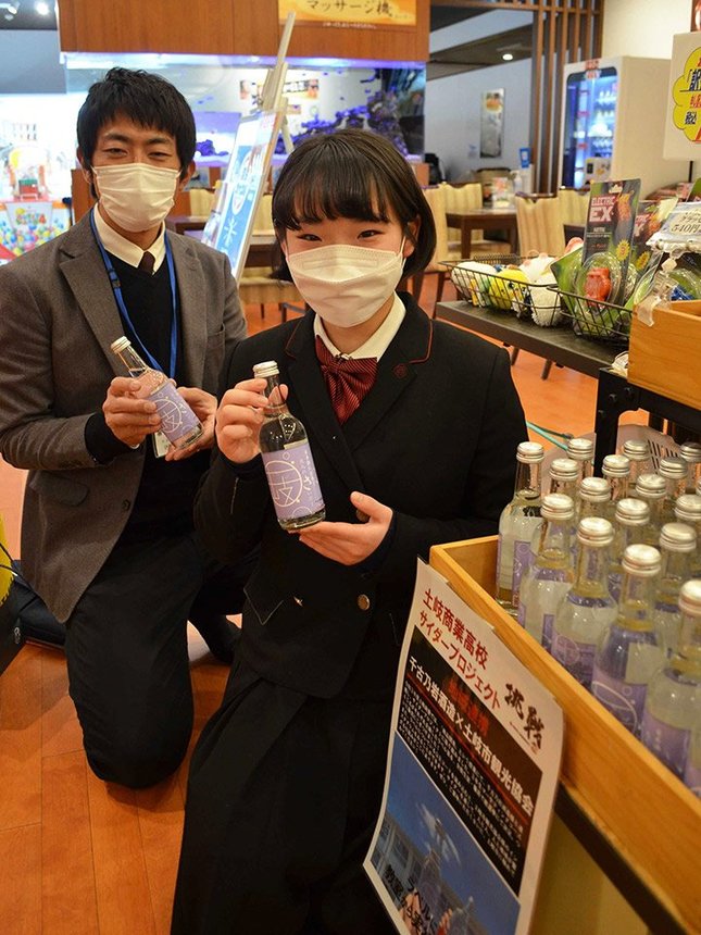 ラベルを考案した「土岐商サイダー」を手にする女子生徒＝土岐市土岐ケ丘、よりみち温泉