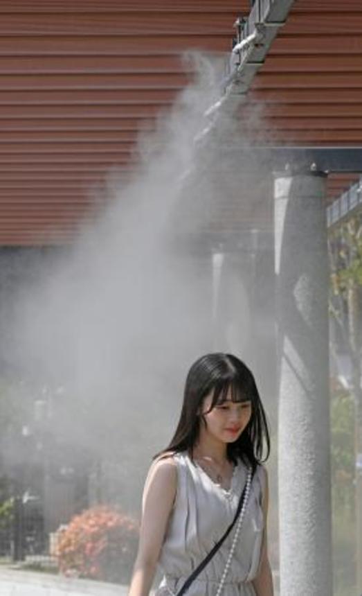　東京・銀座でミストシャワーを浴びて涼む人＝３１日午後