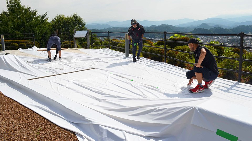 打ち上げ会場を防炎シートで養生するスタッフ＝高山市上岡本町、アルプス展望公園スカイパーク