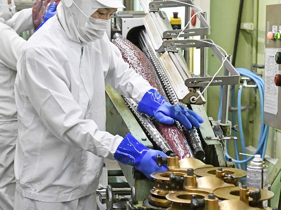 裁断のため、ドリルのような機械にあめ生地を巻き付ける。裁断直前にオリジナルの梅肉ペーストを注入する＝各務原市鵜沼各務原町、桃太郎製菓