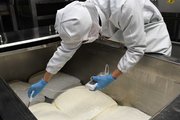 チーズの原料となるカードのｐＨを測る従業員