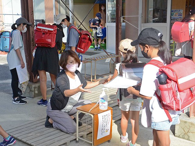 健康チェックカードの確認を受けて校舎に入る児童＝中津川市東宮町、東小学校