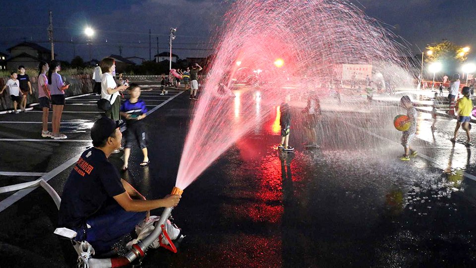 水を浴びて楽しむ子どもたち＝池田町六之井、町中央公民館南駐車場