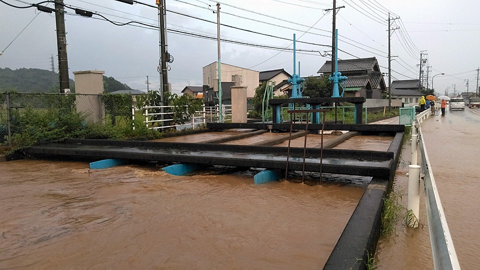 水路の水が道路にあふれ冠水。関係者らが対応に追われた＝１６日午後、関市下有知
