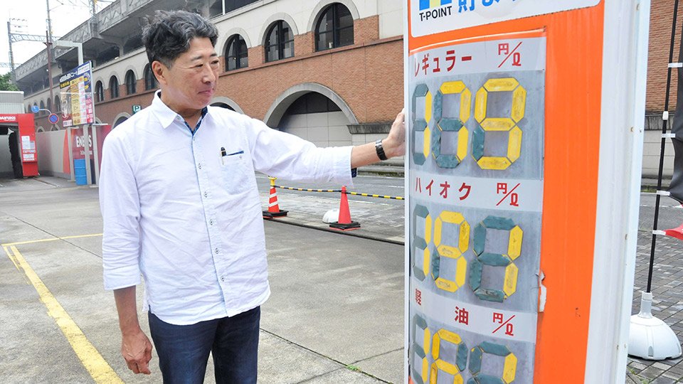 高い水準が続くガソリン価格を示す看板を見つめる和田隆社長＝２１日、岐阜市橋本町、ＥＮＥＯＳドクタードライブ岐阜駅前店