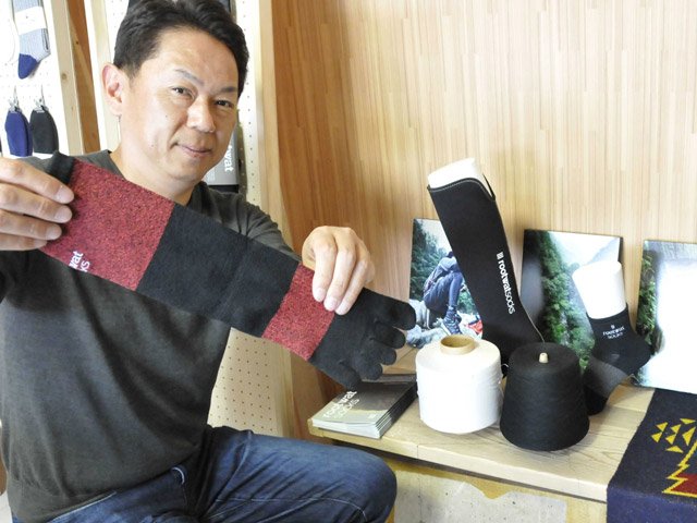 今月、釣り用に発売を始めた５本指の靴下と水谷顕治社長＝関市保明、東洋繊維