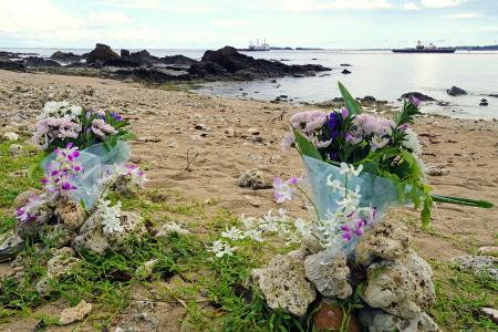 　転覆事故の現場海域を臨む浜辺に手向けられた花束＝１６日午後、沖縄県名護市
